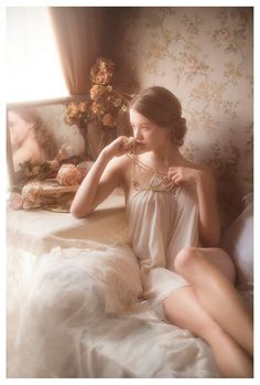 Woman in a bedroom with soft lighting, holding a pearl necklace