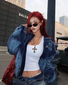 Woman with red hair in a denim jacket and crop top on an urban street