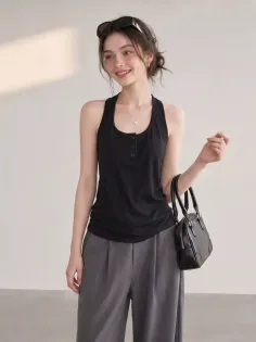 Woman in a black tank top and wide leg pants holding a small handbag