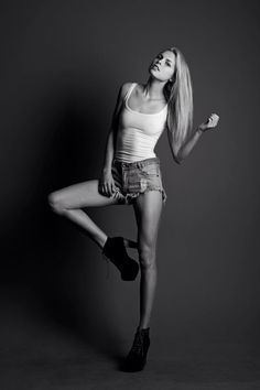 Woman in a tank top and denim shorts posing in a studio