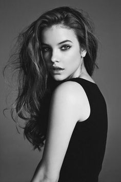 Woman with long hair in a black top looking over her shoulder