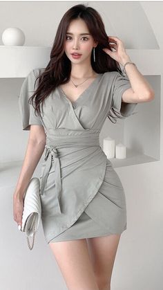 Woman in a light green wrap dress with long dark hair indoors