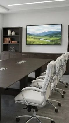 Modern conference room with a long table, white chairs, and a flat screen TV