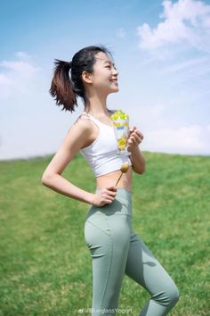 Woman in a white crop top and green leggings holding a dessert outdoors
