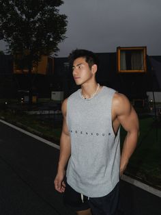 Muscular man in a grey sleeveless shirt and shorts outdoors at night