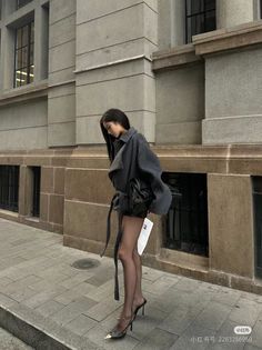 Woman in a gray coat and black tights on a city street