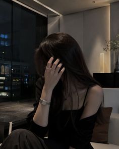 Woman with long dark hair indoors at night with a cityscape view