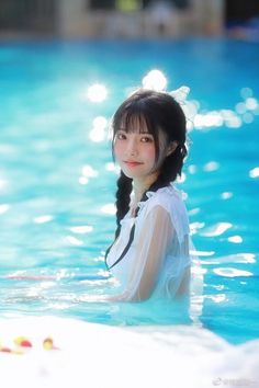 Woman with twin tails in a white sheer dress in a swimming pool