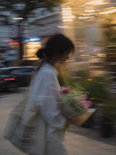 Woman with a flower bouquet walking on a city street at golden hour with motion blur