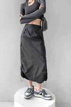 Person in a dark gray long sleeve crop top and cargo skirt with sneakers