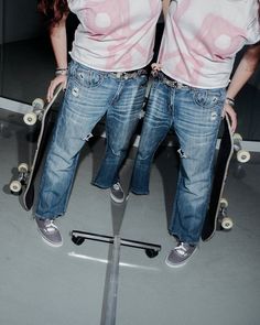Two people in ripped jeans and sneakers holding skateboards indoors