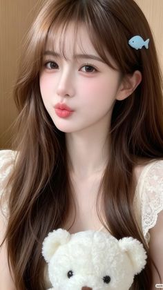 Woman with long brown hair and a blue fish hair clip holding a white teddy bear