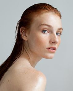 Woman with wet red hair and bare shoulders looking over her shoulder