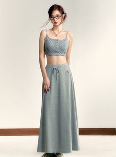 Woman in a polka dot crop top and long gray skirt with glasses