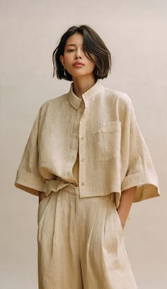Woman with short hair wearing a beige cropped shirt and wide leg pants