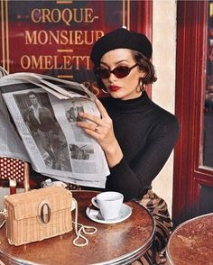 Woman in a beret and sunglasses reading a newspaper at a cafe
