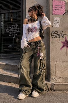 Woman in cargo pants and an off-shoulder top with headphones in an urban setting
