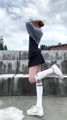 Person with red hair in a mini skirt and long socks posing outdoors