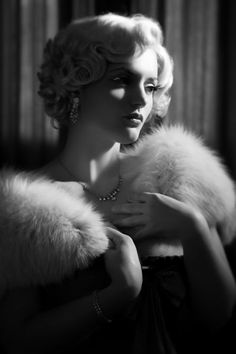 Woman with blonde curly hair and a fur stole in a dramatic black and white portrait