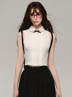 Woman with long hair and glasses wearing a white top and black skirt