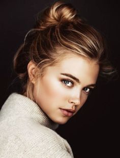 Woman with blonde hair in a messy bun wearing a turtleneck sweater