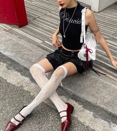 Person in a black crop top and white lace stockings sitting outdoors
