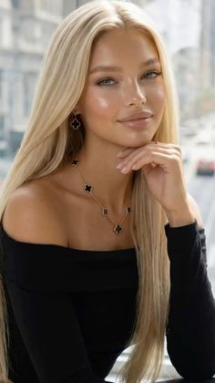 Blonde woman in an off-shoulder top with jewelry, posing indoors