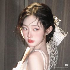 Woman with dark hair and pearl earrings wearing a white lace dress