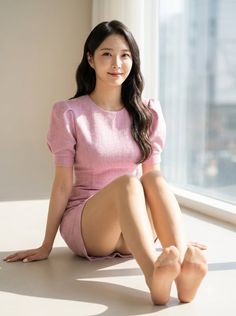 Woman in a pink dress sitting on the floor by a window with soft lighting