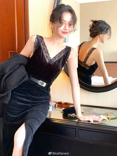Woman in a black lace-trim dress with an updo, posing indoors