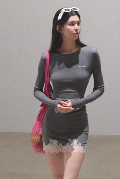 Woman in a gray dress with white lace trim and a pink mesh bag