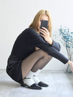 Woman with long blonde hair taking a mirror selfie while squatting