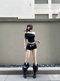 Woman with black hair wearing an off-shoulder top and shorts outdoors
