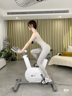 Woman in a gray sports bra and leggings on an exercise bike indoors