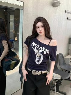 Woman with long dark hair wearing an off-shoulder top and black pants outdoors