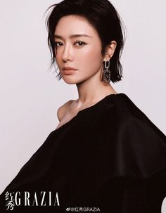 Woman with short hair and earrings wearing a black top with an exposed shoulder