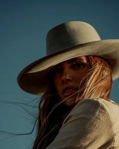 Woman with long red hair and a cowboy hat looking over her shoulder