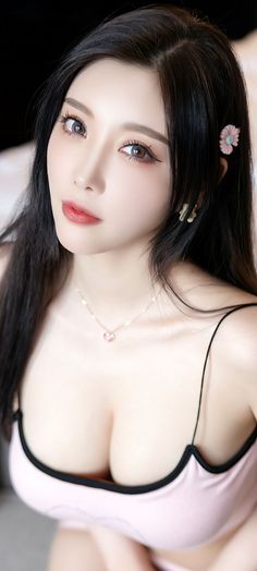 Woman with long black hair wearing a pink top and heart necklace