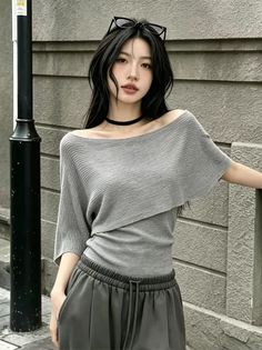 Woman with long dark hair wearing an off-shoulder top and choker in an urban setting