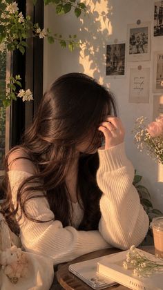 Woman with long hair in a white sweater, bathed in golden hour light indoors
