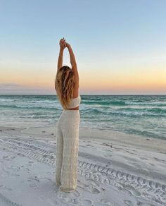 Woman with long wavy hair stretching on a beach at sunset