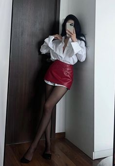 Woman in a red mini skirt and white shirt taking a mirror selfie
