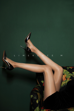 Woman's legs in high heels and pantyhose resting on a floral armchair