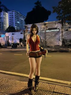 Woman in a red corset top and short shorts standing on a city street at night