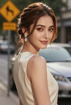 Woman with an updo and diamond earrings looking over her shoulder outdoors
