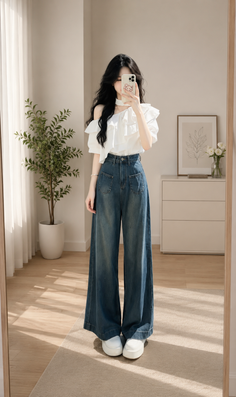 Woman in a white ruffle top and wide leg jeans taking a mirror selfie