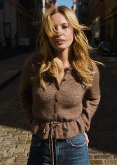 Woman with blonde hair in a brown cardigan and jeans on a street