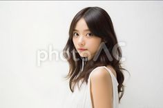 Woman with long dark hair in a white dress against a white background