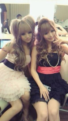 Two women with long hair wearing dresses, posing indoors