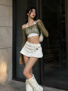 Woman in a white mini skirt and green mesh crop top with white boots